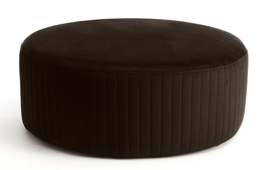 Pufa Lara w kolorze Monolith 29 brązowy, okrągła, tapicerowana welurem z pionowym przeszyciem na bokach, prezentowana na białym tle.