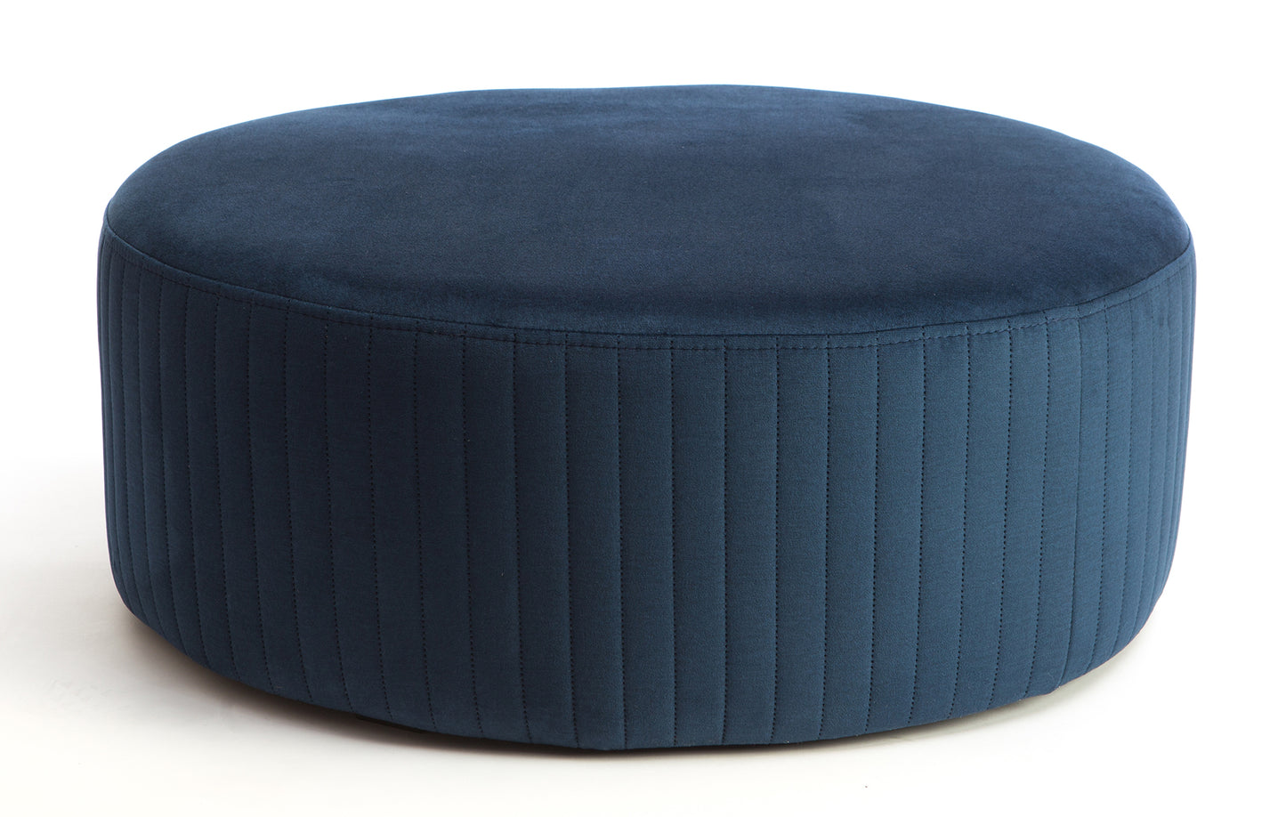 Pufa Lara w kolorze Monolith 77 niebieski, okrągła, tapicerowana tkaniną welurową z pionowym przeszyciem na bokach, prezentowana na białym tle.