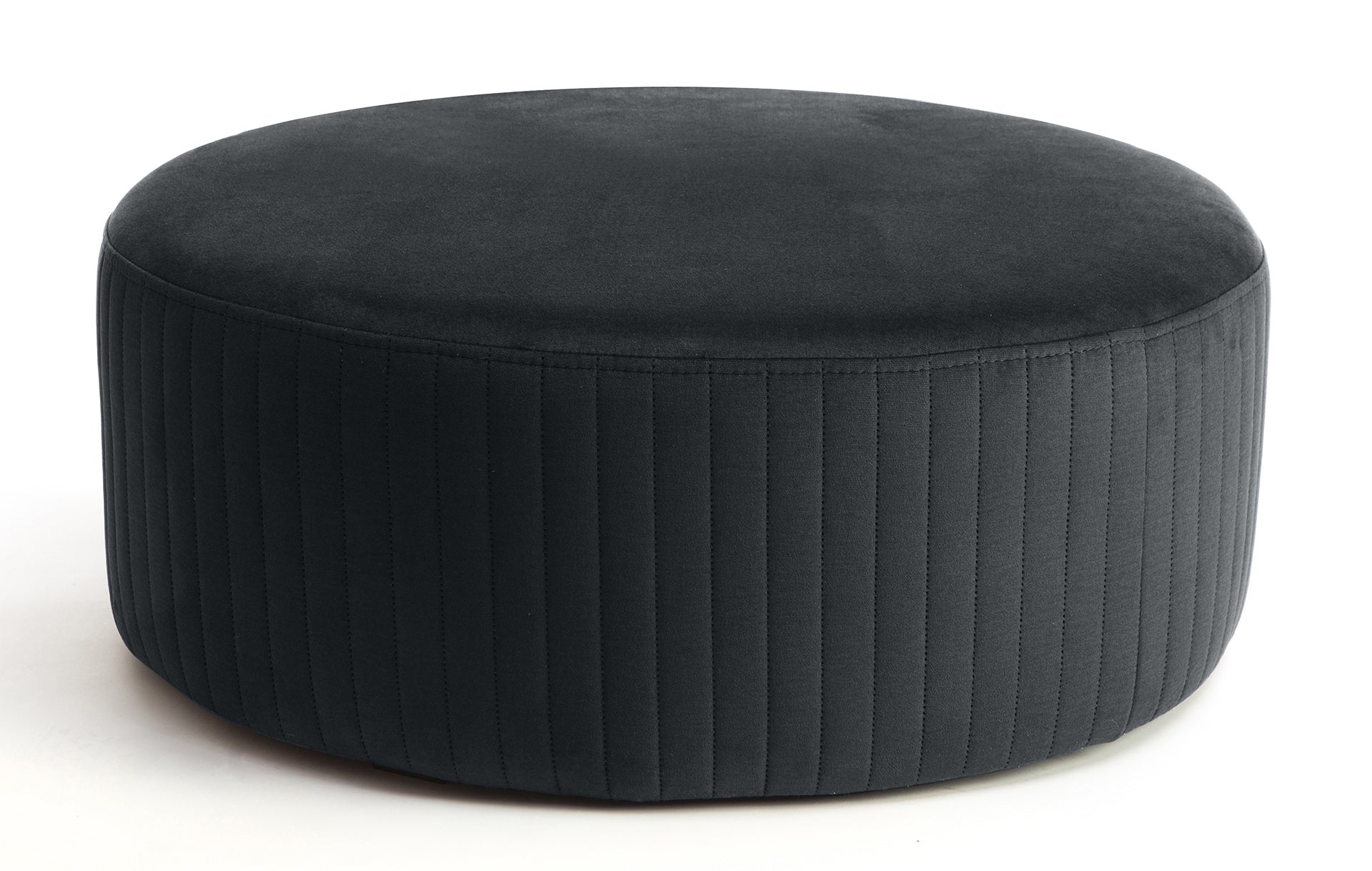 Pufa Lara w kolorze Monolith 97 ciemnoszary, okrągła, tapicerowana welurem z pionowym przeszyciem po bokach, prezentowana na białym tle.