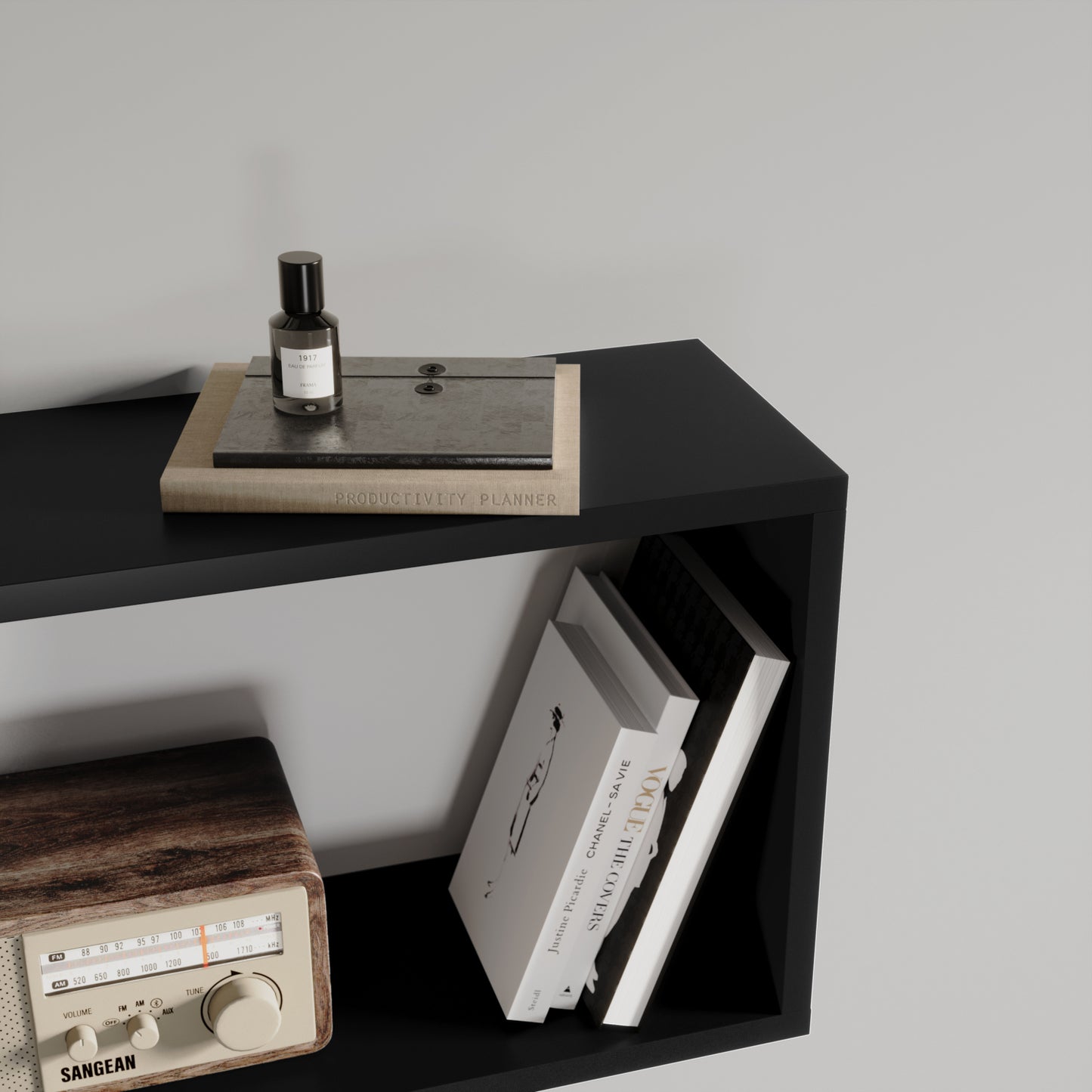 Górna półka czarnego regału Evertti z notatnikiem, perfumami i książkami – stylowe, minimalistyczne ujęcie w nowoczesnym wnętrzu.