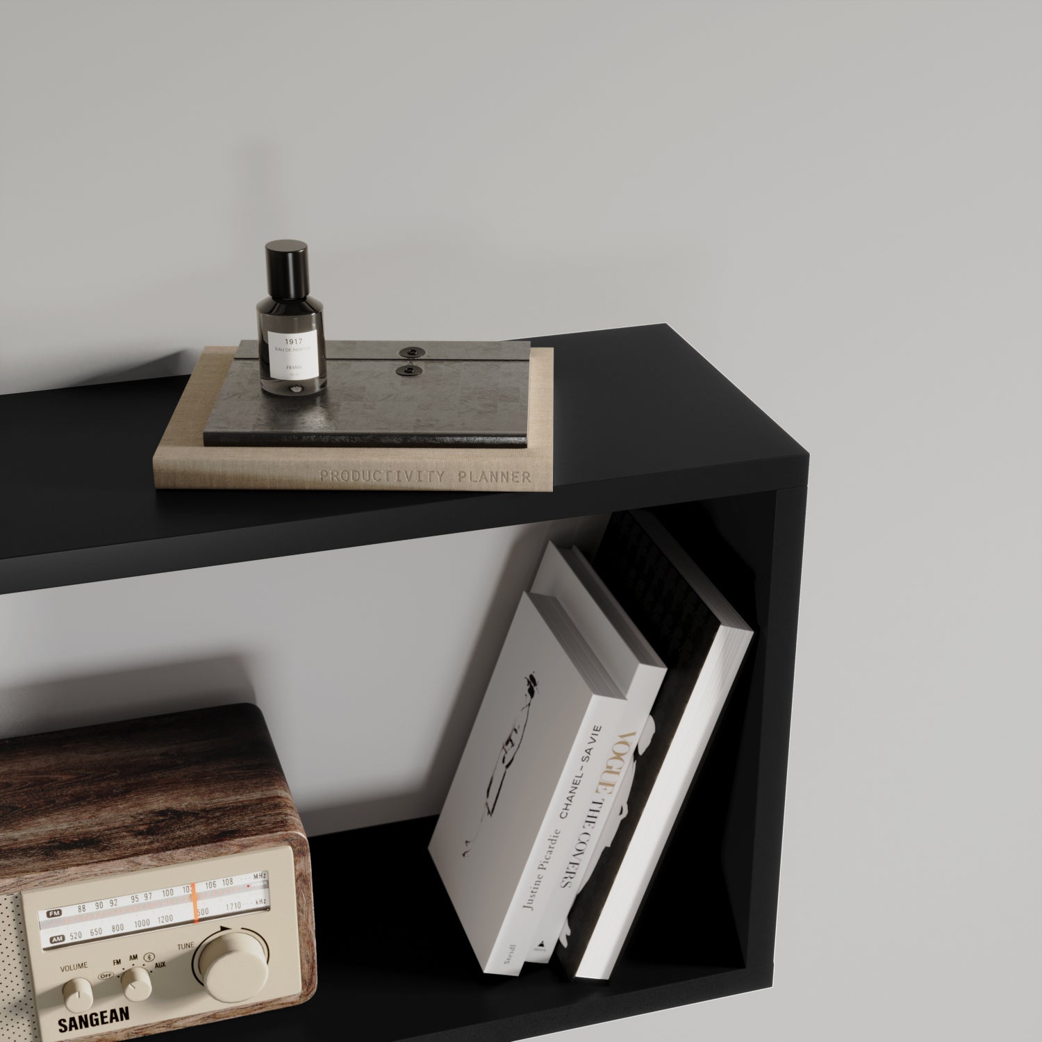 Górna półka czarnego regału Evertti z notatnikiem, perfumami i książkami – stylowe, minimalistyczne ujęcie w nowoczesnym wnętrzu.