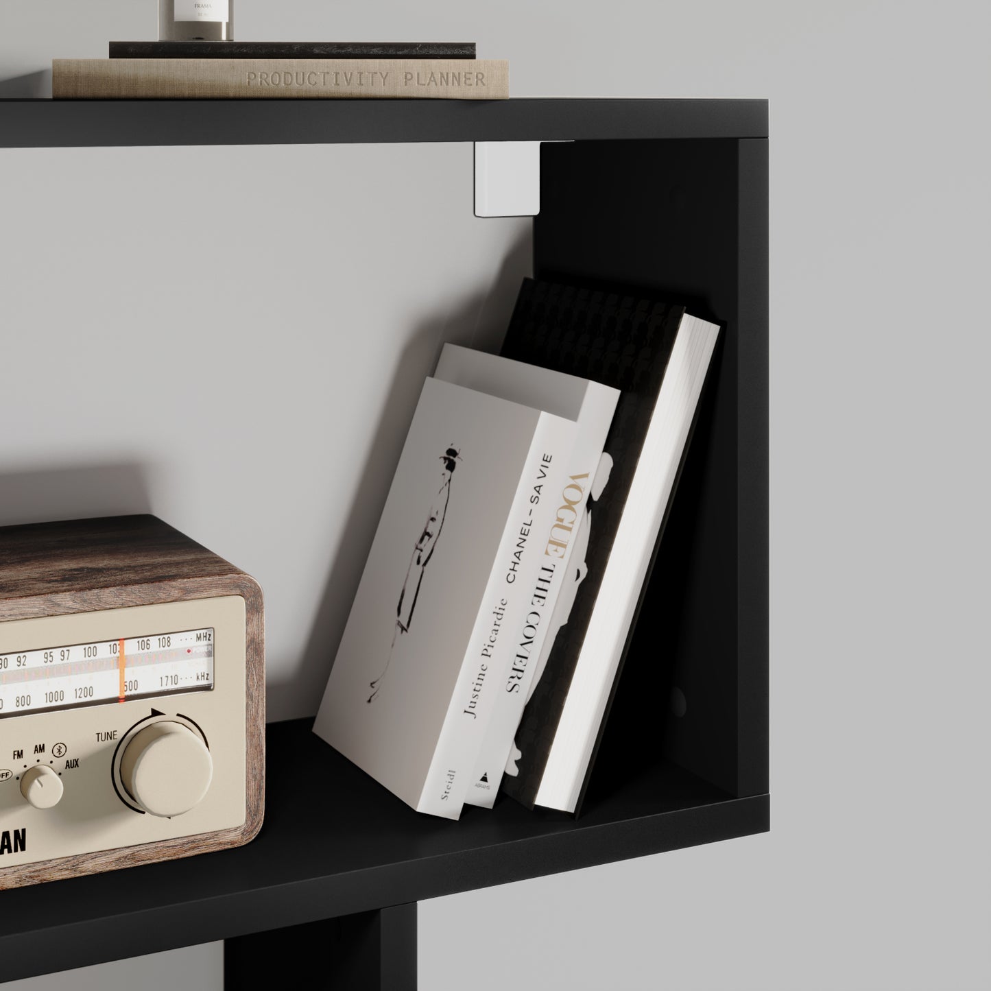 Półka czarnego regału Evertti z drewnianym radiem retro i książkami ustawionymi pod kątem – detal nowoczesnego wnętrza.