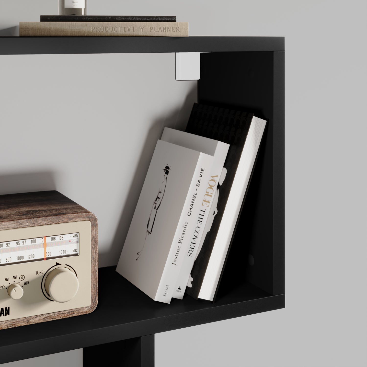 Półka czarnego regału Evertti z drewnianym radiem retro i książkami ustawionymi pod kątem – detal nowoczesnego wnętrza.