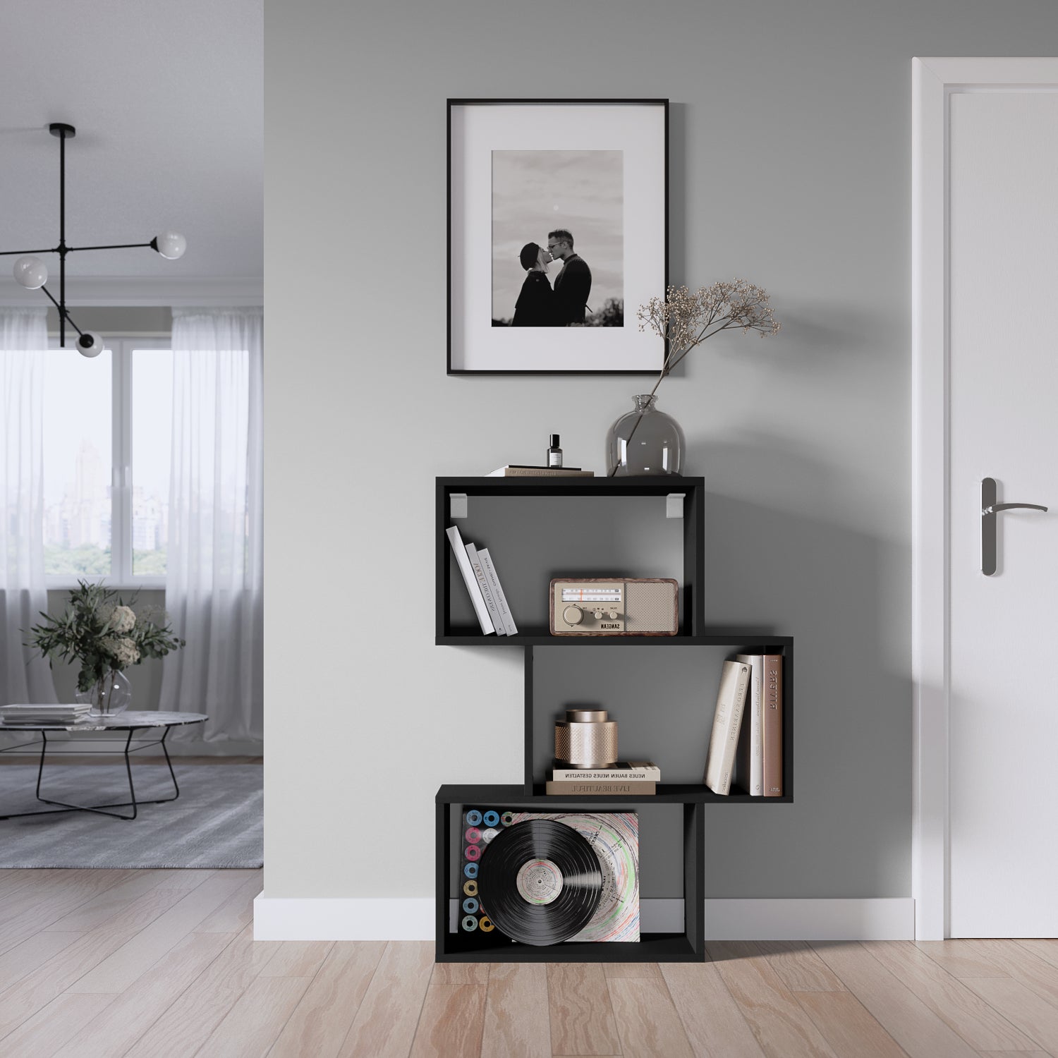 Nowoczesny czarny regał Evertti w salonie, ustawiony przy ścianie, wypełniony książkami, ozdobami i płytami winylowymi.