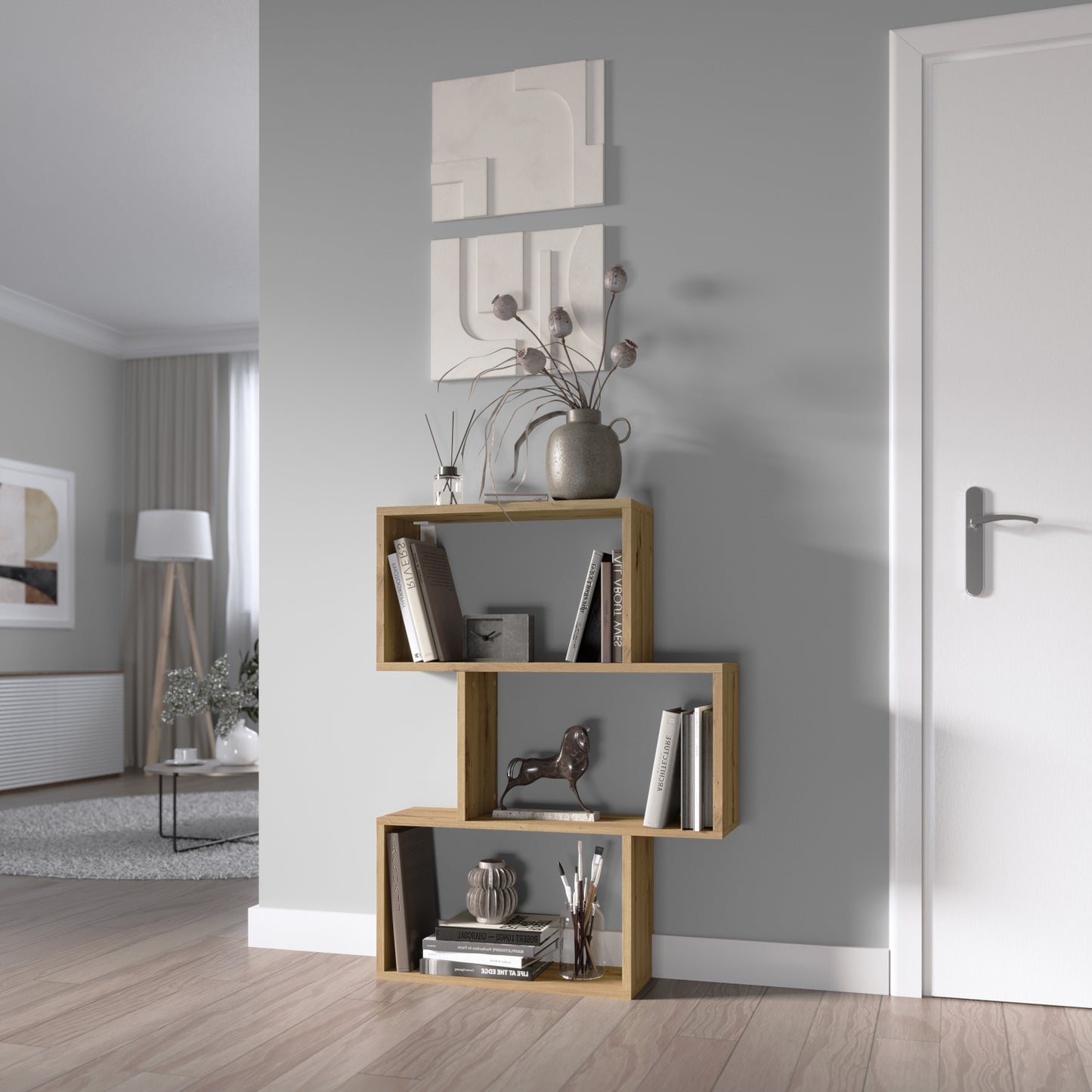 Regał Evertti w kolorze dąb artisan w nowoczesnym salonie. Asymetryczna konstrukcja z dekoracjami i książkami.
