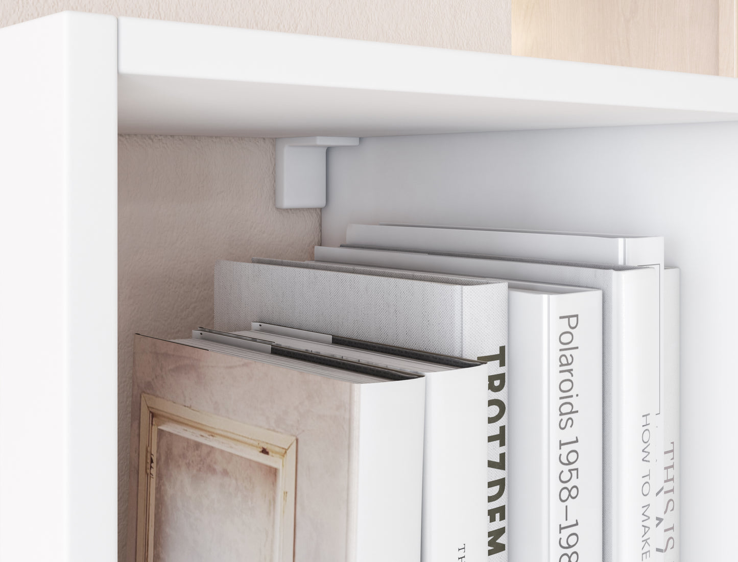 Zbliżenie na biały regał Figgi z książkami w jasnych okładkach, osadzonymi pod górną półką z mocowaniem do ściany.