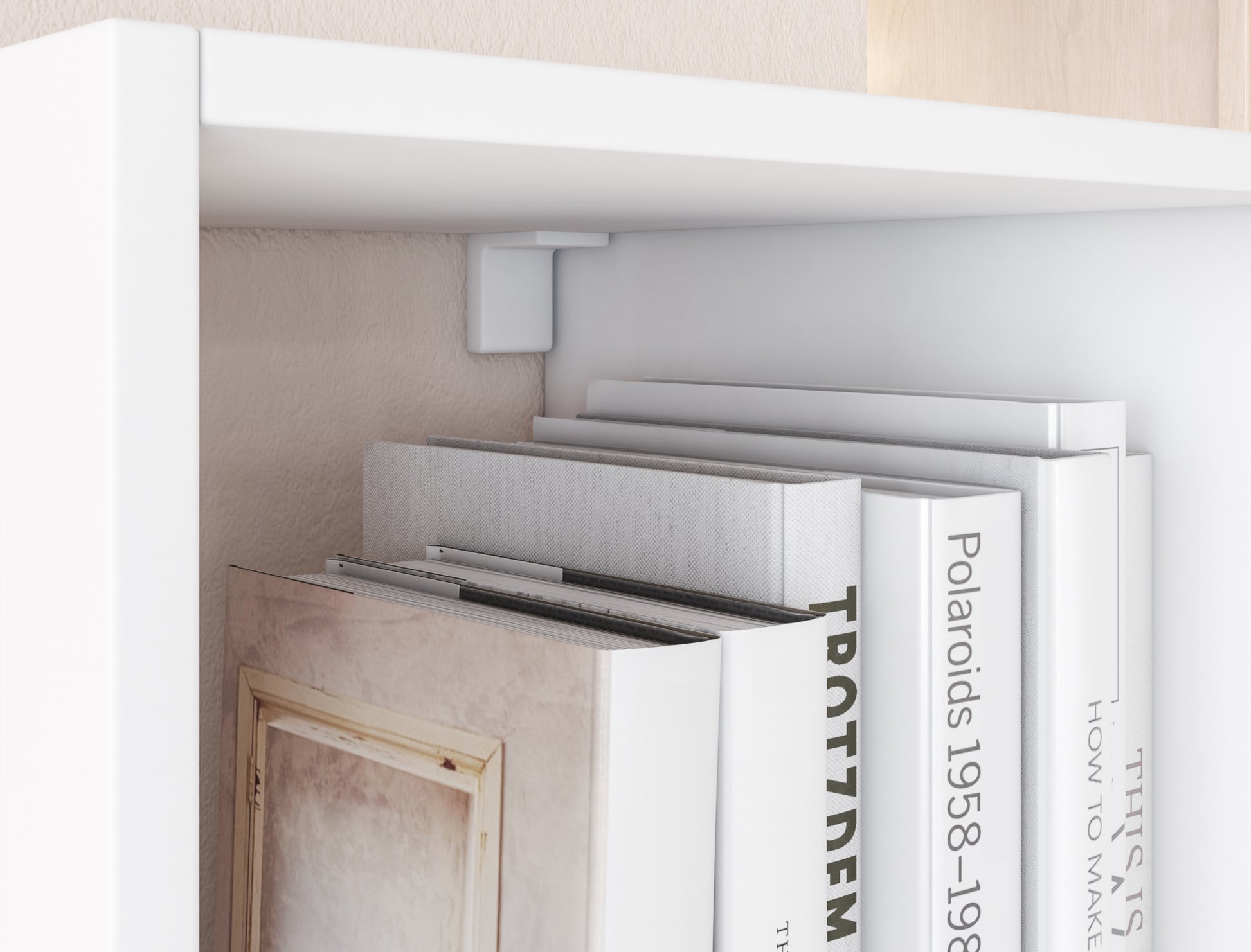 Zbliżenie na biały regał Figgi z książkami w jasnych okładkach, osadzonymi pod górną półką z mocowaniem do ściany.