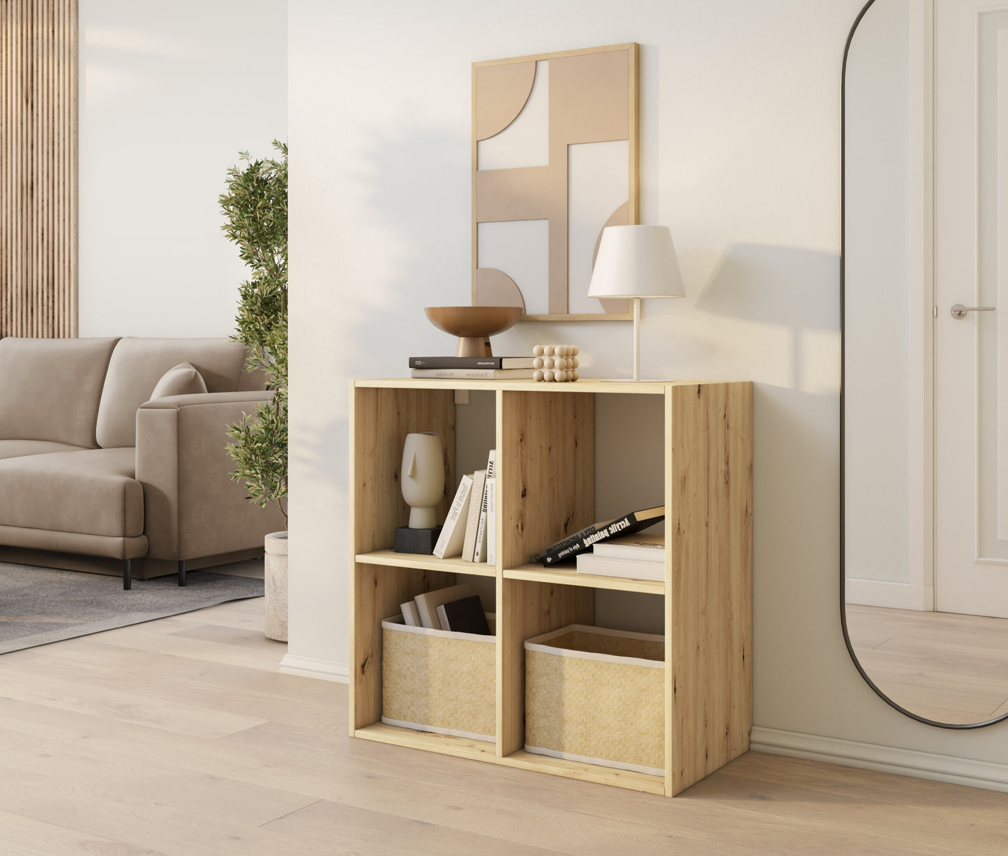 Regał Jugis w kolorze dąb artisan z czterema wnękami, ozdobiony książkami, koszami i lampą, ustawiony w jasnym salonie.