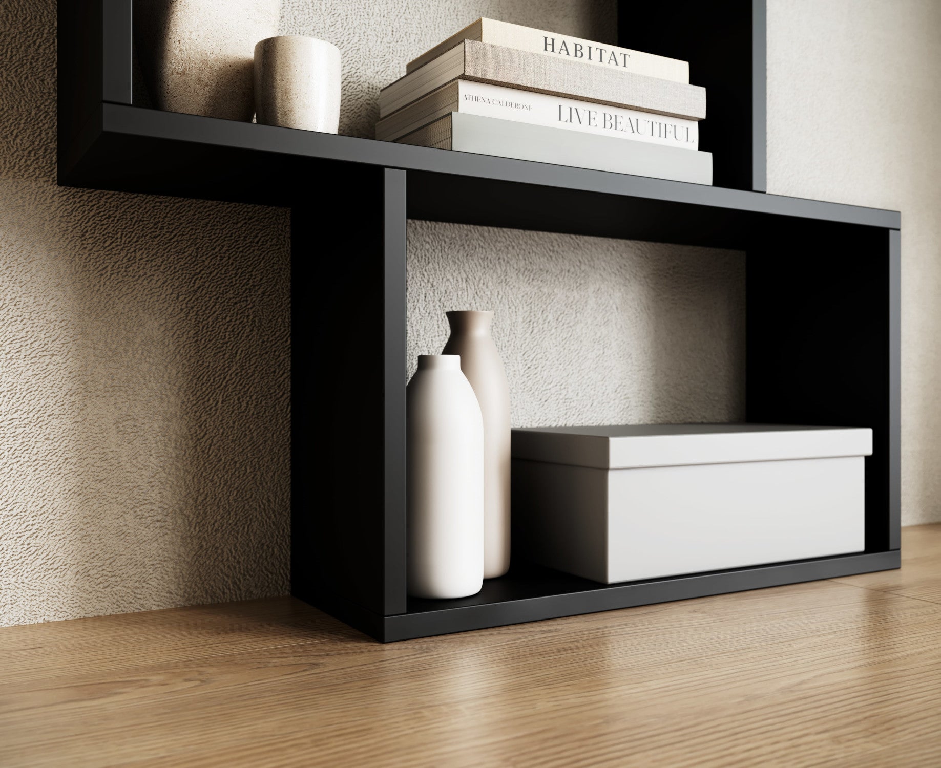 Dolna część czarnego regału Shellf z dekoracjami – dwie matowe wazony w odcieniach beżu i biała pudełkowa skrzynka na tle ściany.