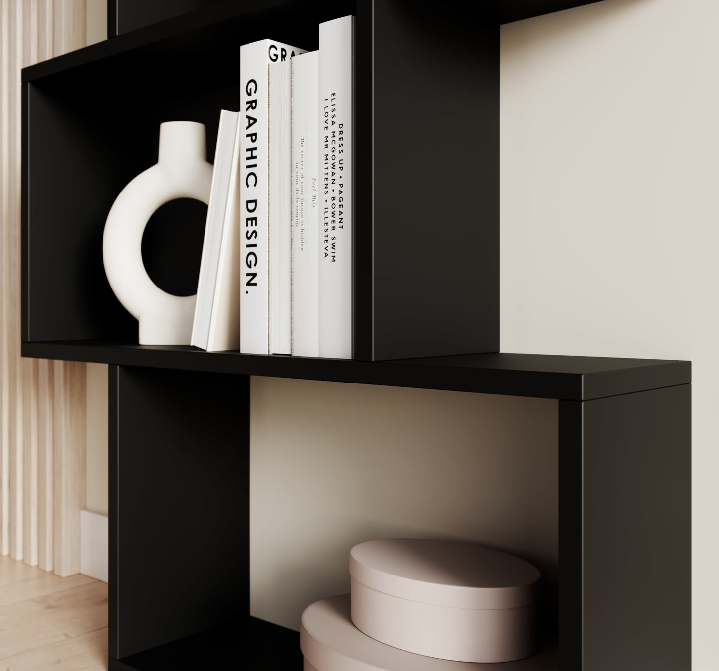Dolna część czarnego regału Sottis z ozdobnymi pudełkami i książkami, w nowoczesnym, minimalistycznym wnętrzu.