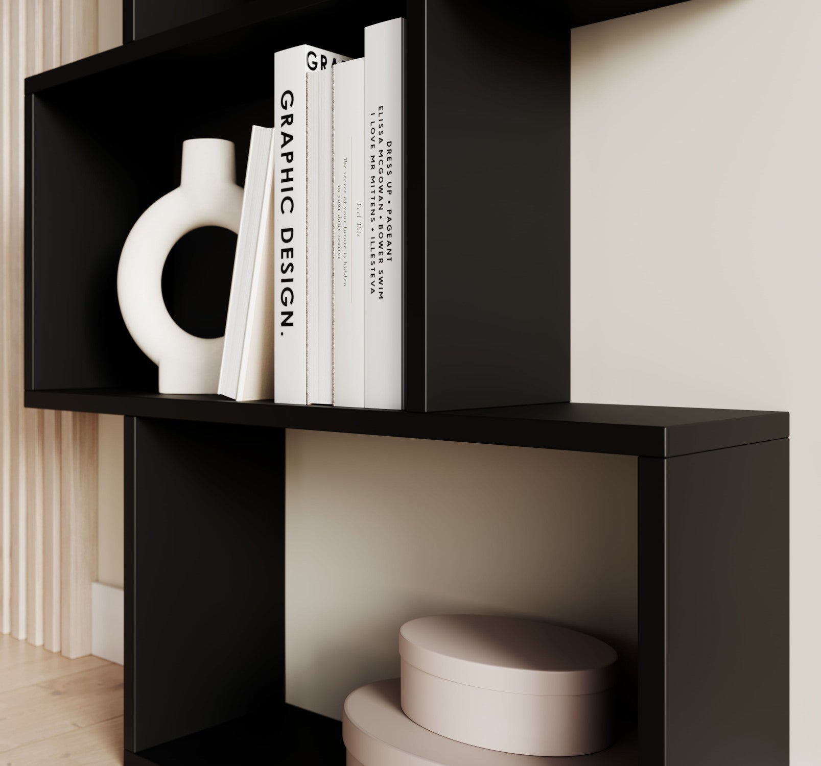 Dolna część czarnego regału Sottis z ozdobnymi pudełkami i książkami, w nowoczesnym, minimalistycznym wnętrzu.