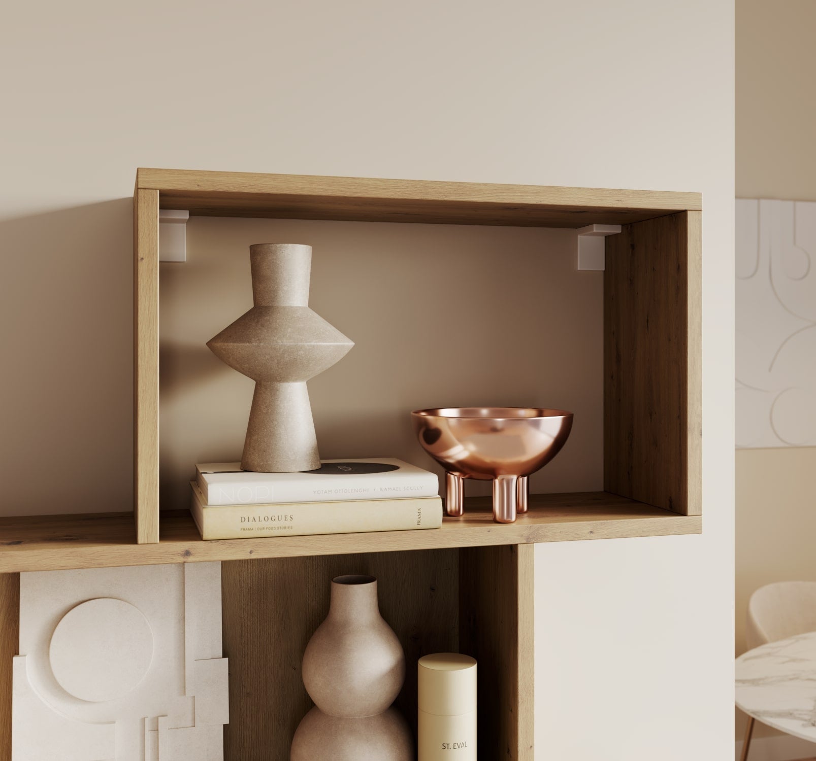 Górna półka regału Sottis dąb artisan z dekoracjami: ceramiczna rzeźba, miedziana misa i stylowe książki na tle jasnej ściany. 
