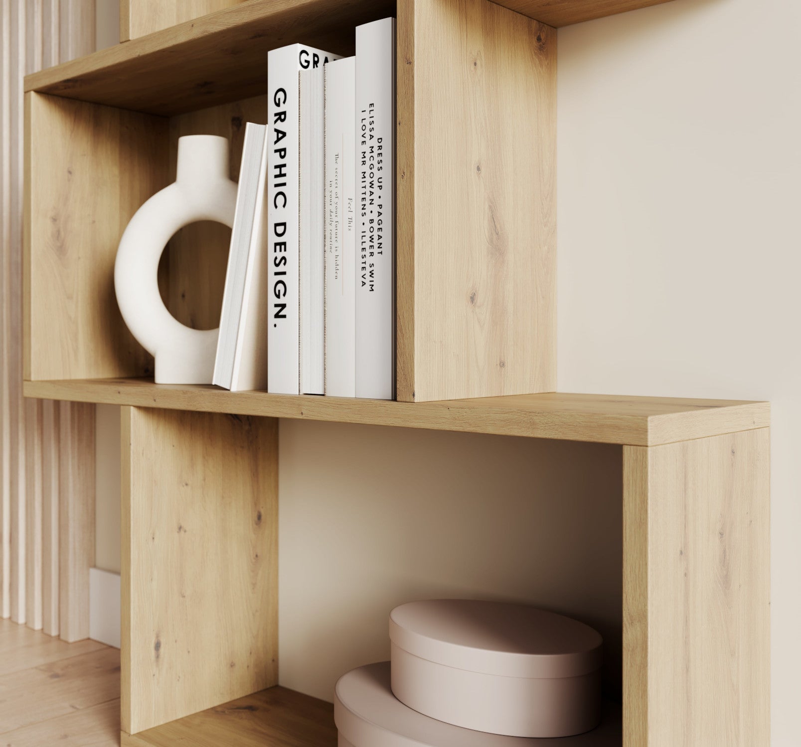 Środkowa część regału Sottis dąb artisan z książkami o designie i dekoracyjną rzeźbą w jasnym, nowoczesnym wnętrzu.