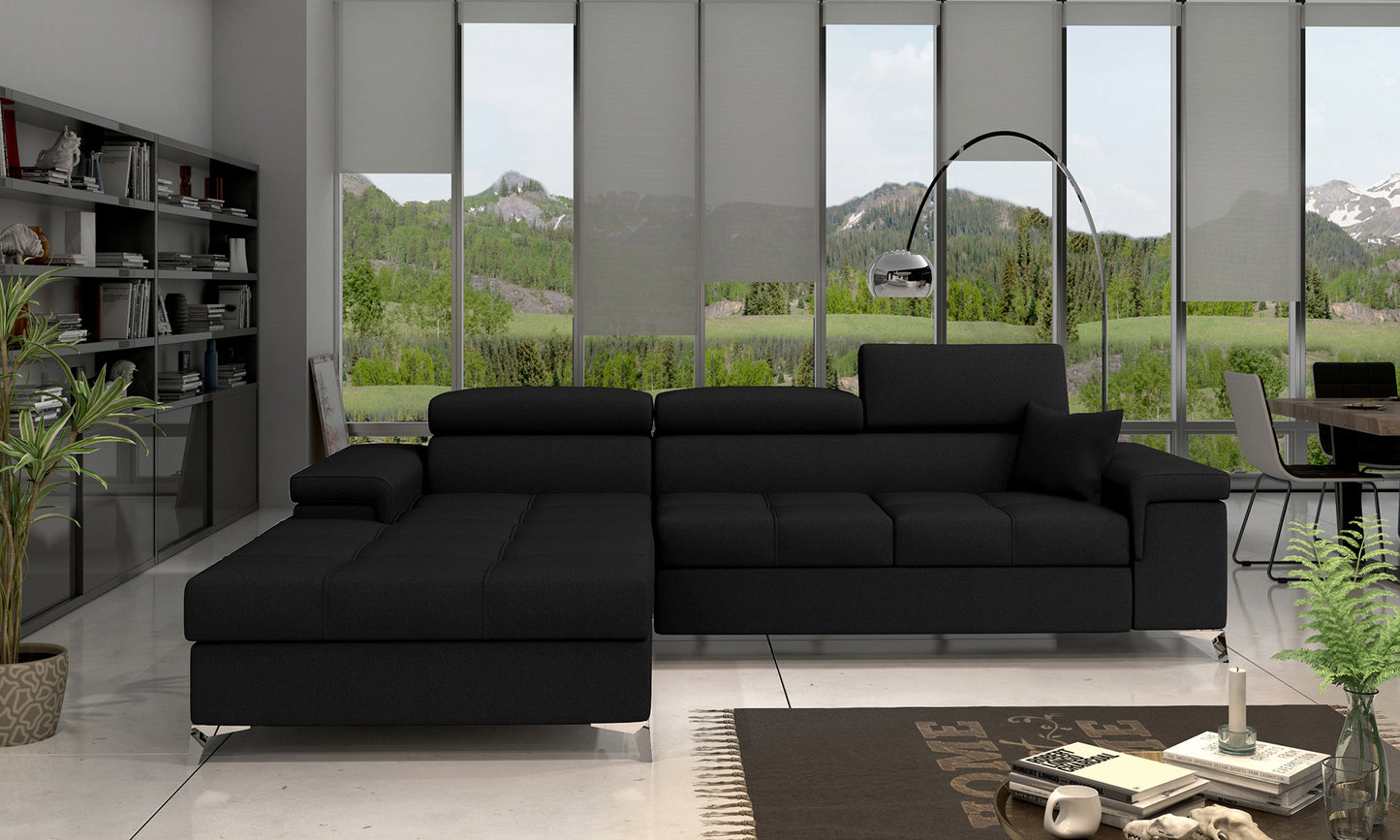 Narożnik Ricardo w układzie lewym, w kolorze Kronos 07 czarny, ustawiony w eleganckim, nowoczesnym salonie na jasnym dywanie, obok stolika kawowego i regału z książkami.