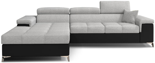 Narożnik Ricardo w układzie lewym, tapicerowany tkaniną Sawana 21 szary z wykończeniem Soft 11 czarny, wyposażony w regulowane zagłówki, szerokie podłokietniki i poduszkę dekoracyjną, prezentowany na białym tle.