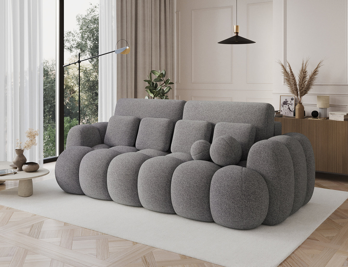 Big Sofa Cotonn w tkaninie Paolli 04 szary, ustawiona w eleganckim salonie, z dużymi poduchami i zaokrąglonymi bokami.