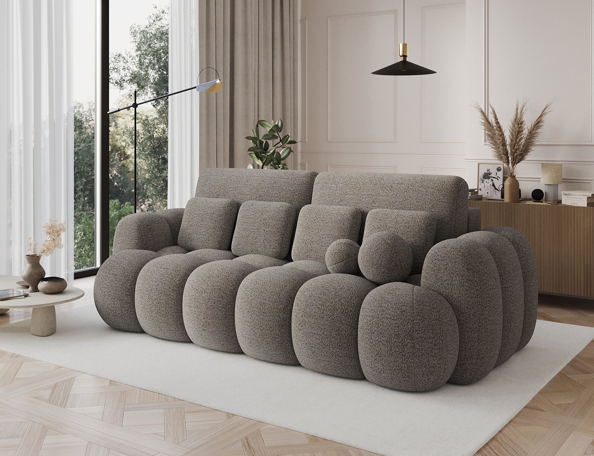 Sofa Cotonn Royal 20 w kolorze beżowym – ustawiona w eleganckim salonie, ukazana pod kątem, z dekoracyjnymi poduchami i zaokrąglonymi formami.