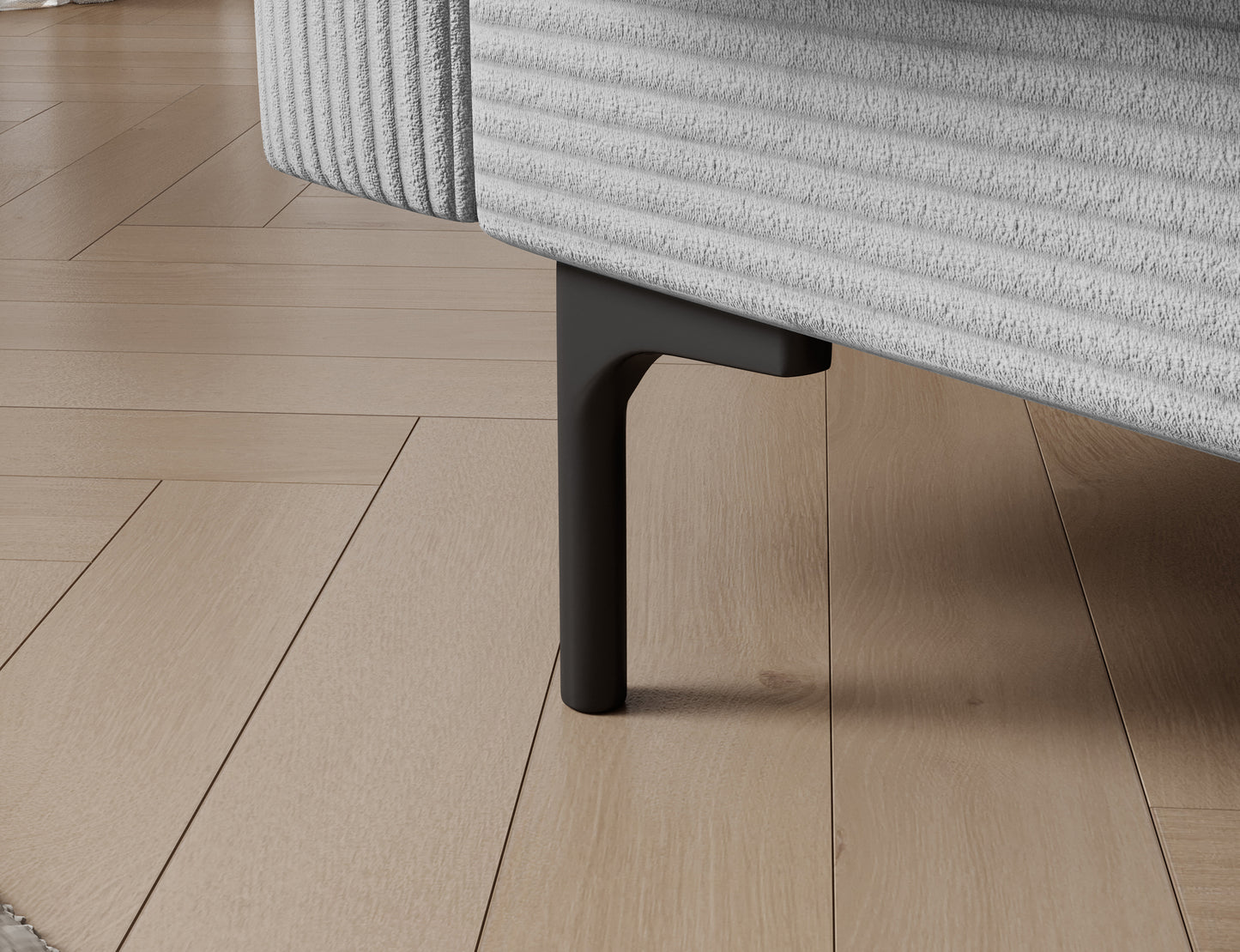 Plastikowa nóżka sofy Roneyy w stylu loft, detal wykończenia mebla w tkaninie Jarell 04 jasnoszary.