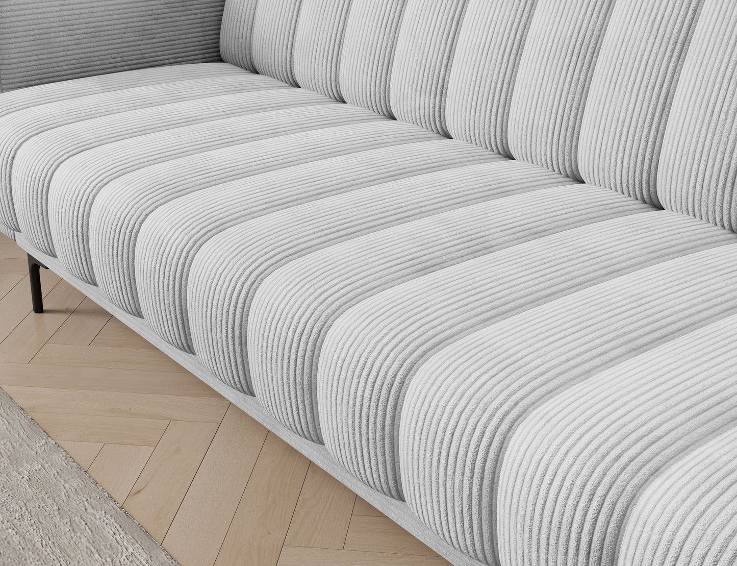 Siedzisko z charakterystycznym pikowaniem w sofie Roneyy tapicerowanej tkaniną Jarell 04 w jasnoszarym kolorze.