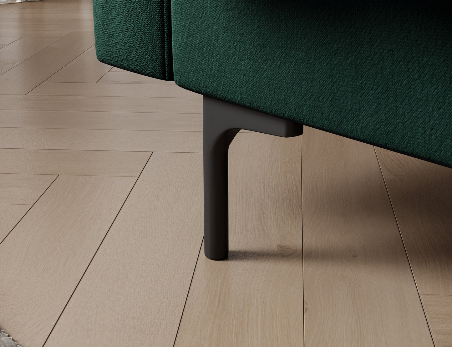 Czarna metalowa nóżka sofy Roneyy Lukso 35 zielony na tle drewnianej podłogi – detal podkreślający lekkość i stabilność mebla