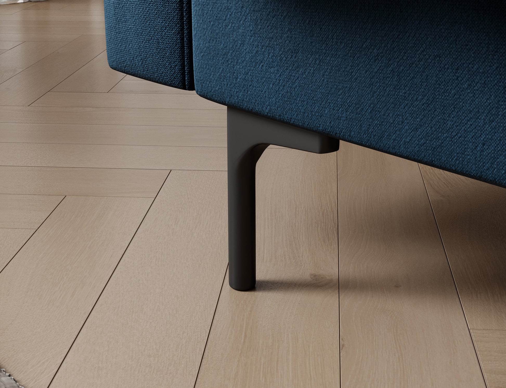Plastikowa, smukła nóżka w sofie Roneyy – detal podkreślający nowoczesny design i stabilność granatowej sofy tapicerowanej.