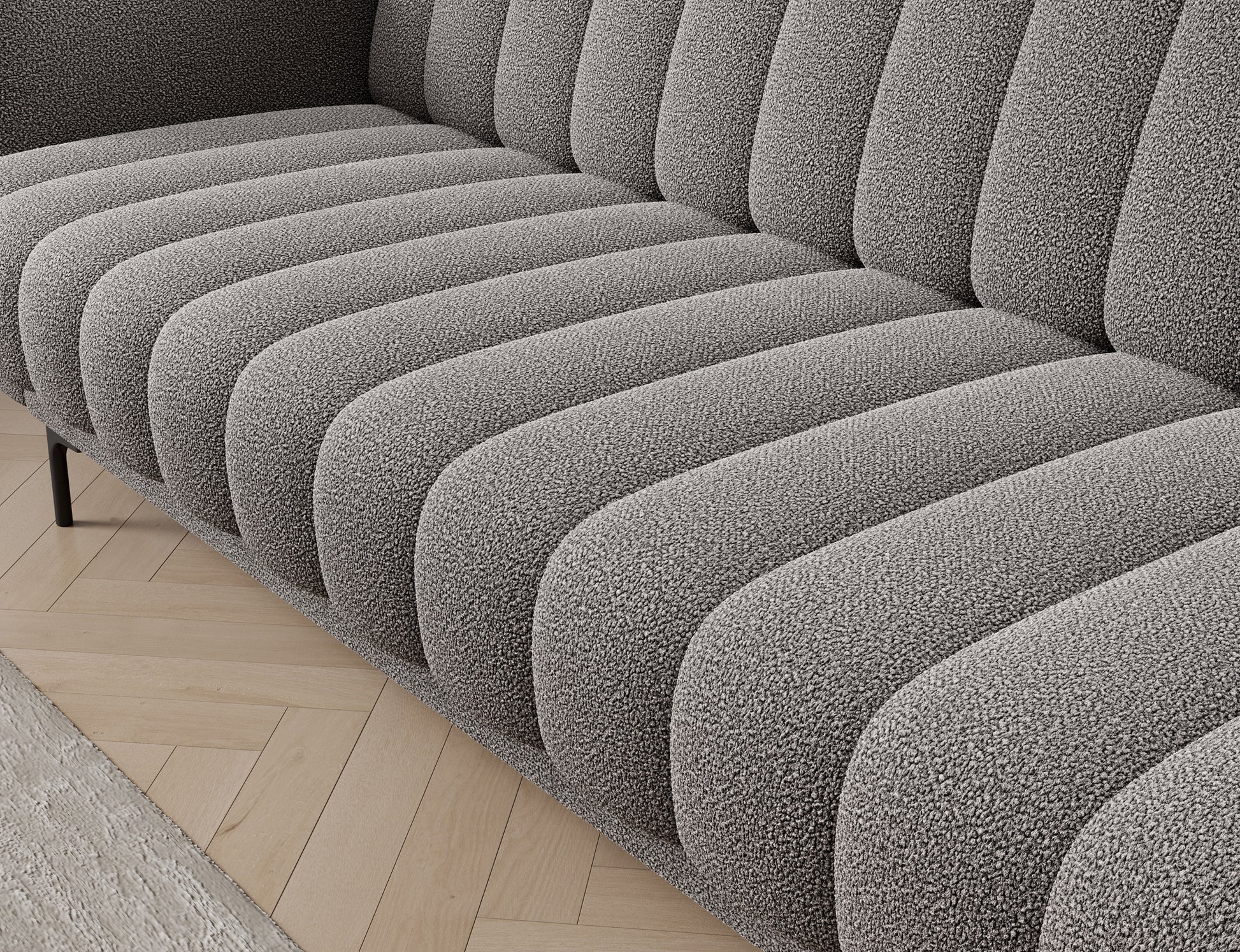 Tapicerowane siedzisko sofy Roneyy Xillar 04 szary z pionowymi przeszyciami i miękkim, profilowanym wykończeniem.