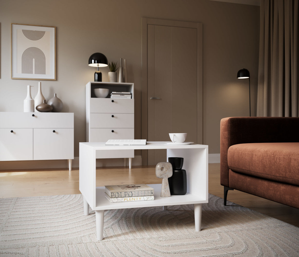 Aranżacja salonu z białym stolikiem kawowym Dullum – mebel w centrum kadru z książką i dekoracją, obok kanapy i designerskich lamp.