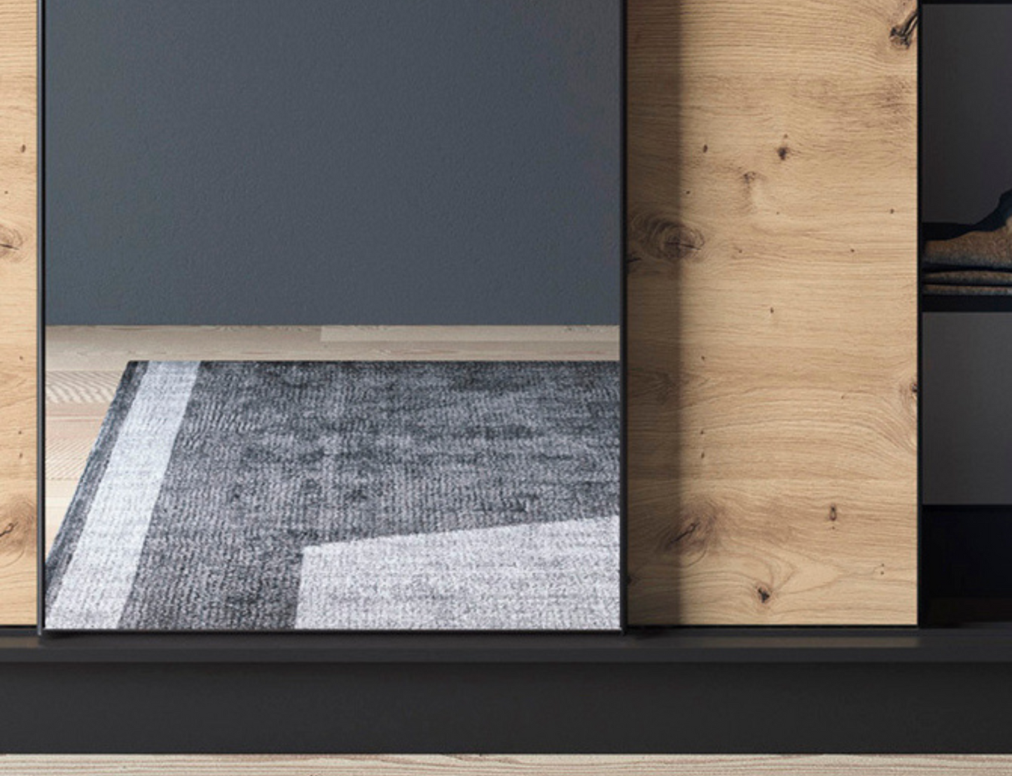 Zbliżenie na strukturę frontów szafy Esville III czarny dąb artisan z ryflowaniem i dużym praktycznym lustrem