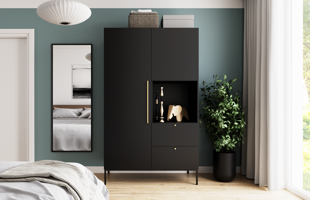 Szafa Lanzzi w czarnym macie ustawiona przy zielonej ścianie obok wysokiego lustra i rośliny doniczkowej, na tle jasnego lnianego zasłony i drewnianej podłogi.