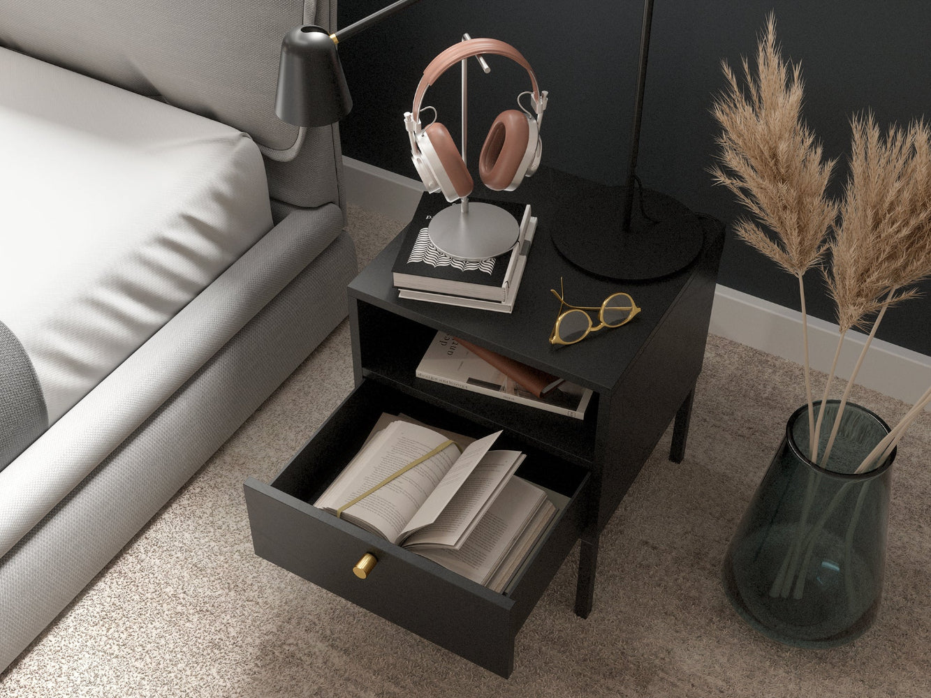Zbliżenie na górną część czarnej szafki nocnej Lanzzi z lampką i stojakiem na słuchawki, pokazujące otwartą półkę z książkami oraz szufladę z wysuniętym frontem i eleganckim, złotym uchwytem.