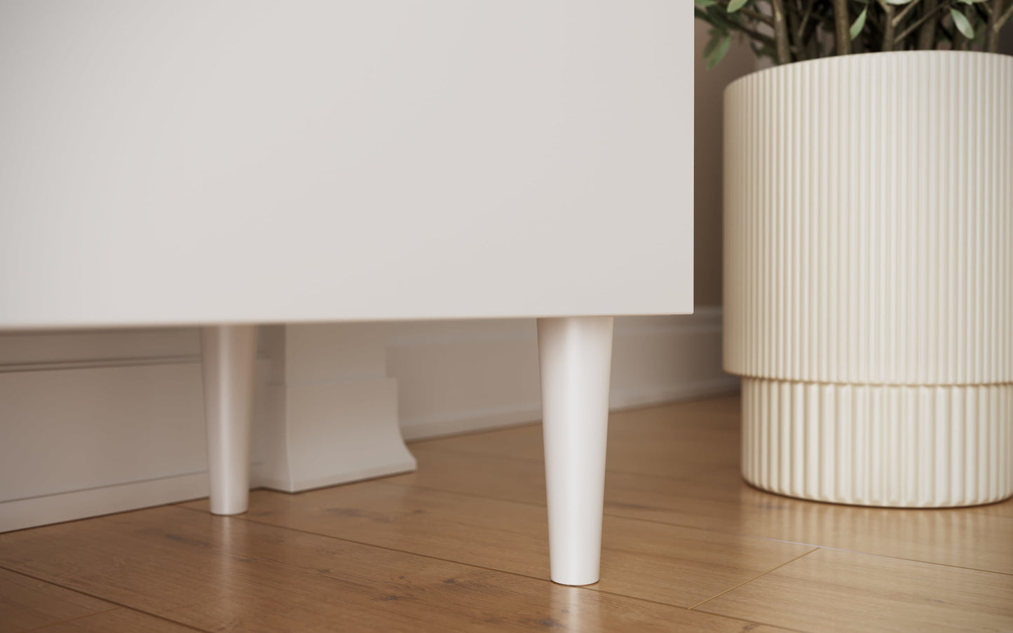 Zbliżenie na białe, stożkowe nogi szafki RTV Dullum – detal podkreślający lekkość konstrukcji i skandynawski design.