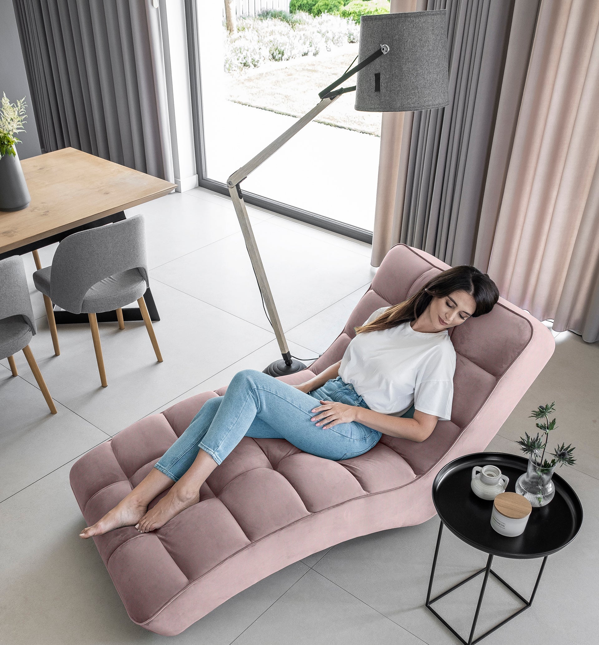 Kobieta relaksująca się na szezlongu Loren Loco 24 jasnoróżowy w eleganckim wnętrzu.