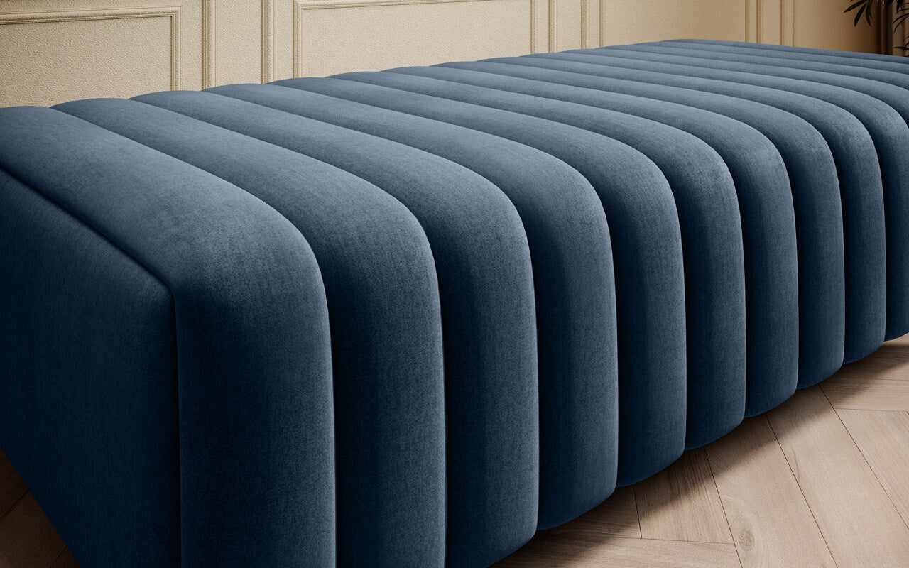 Tapicerowana pufa ławka Laurence w kolorze ciemny petrol, wykonana w tkaninie Nube 40, z dekoracyjnym pionowym przeszyciem i lekkimi metalowymi nóżkami do nowoczesnych wnętrz.